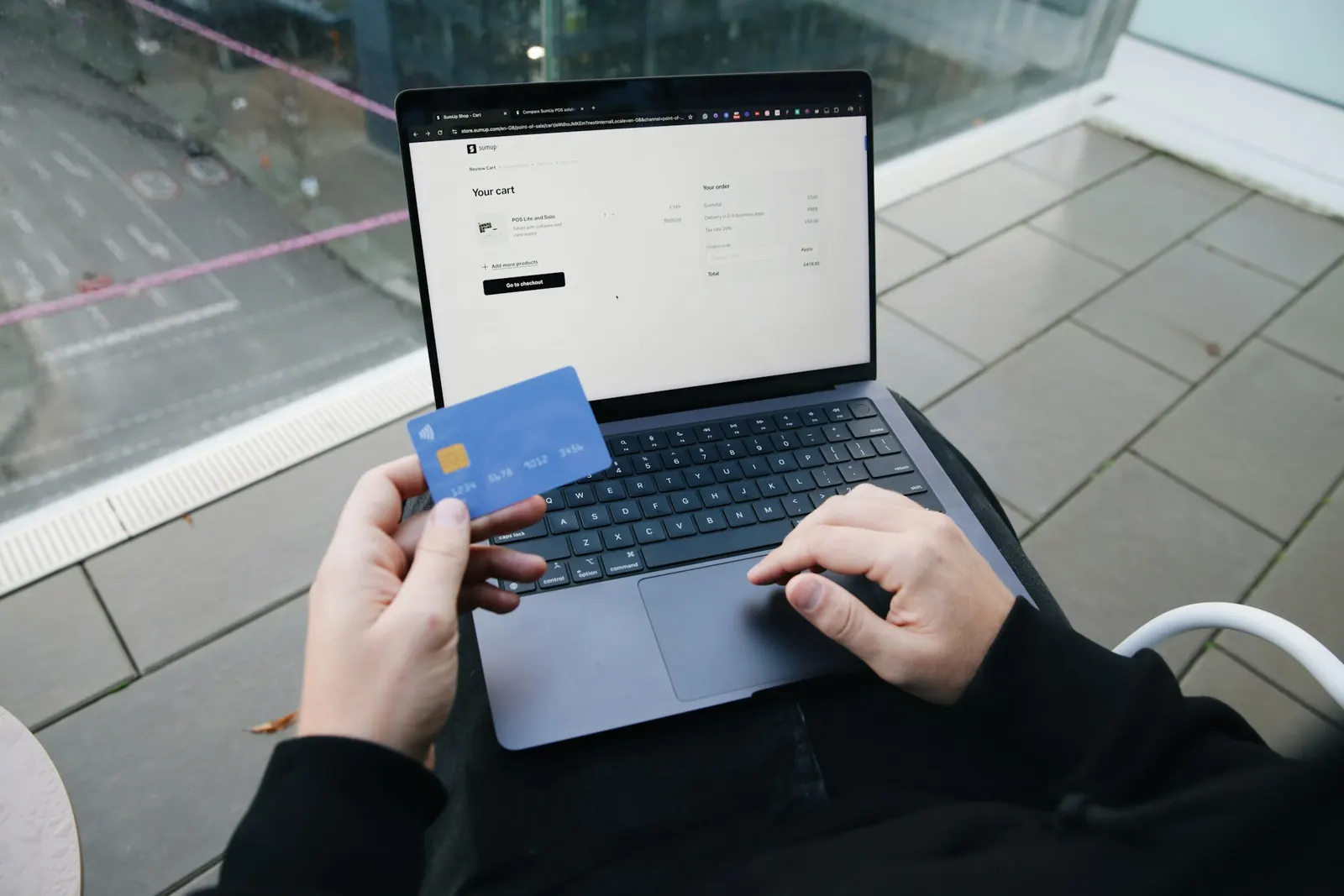 Kupac s bankovnom karticom u ruci dovršava kupnju u web shopu na laptopu
